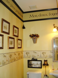 A french wall quote in the toilet room with picture frames on the left side and a lavatory with water closet on the center