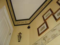 Wall decal near the ceiling with a door on the left side and photo frames on the right