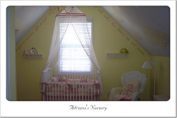 Wall inscriptions just below the ceiling in this pastel motif nursery room with a crib and a hanging crib curtain on the center
