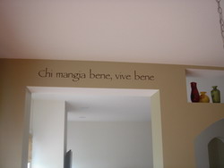 An Italian wall decal on the drop beam ceiling with 3 bottles on the right side - Chi mangia bene, vive bene