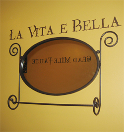 Charming Entrance.La Vita E Bella - wall lettering above the black colored wall decoration.