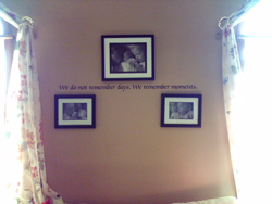A wall decal in between 2 windows with draperies and 3 family photo frames