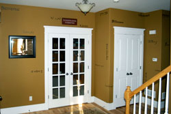 Wall words beside the white colored glass paneled main entrance door with a 1 piece chandelier on the center