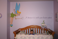 Cutie Pie and her Dream beside Tinkerbell with her magical wand on the center of a lavender wall with a baby crib in the baby's room. A Dream is a wish your heart makes