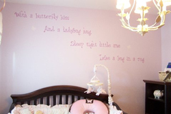 A wall decal in the nursery's room with a wooden crib and a chandelier