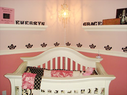 Wall Decal on Top of the two shelves with sconce on the center and a crib below.