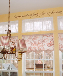 A wall decal in the dining room above the dining windows with chandelier on the center - Enjoying a meal with family or friends is fine dining.