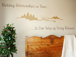 Wall decal with design on the center above the wooden headboard and indoor ornamental plant on the side in the bedroom area