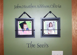 The Seeis a dark green color wall decal with 2 pictures of baby kids on a hallway - John. Heather, Addison, Olivia