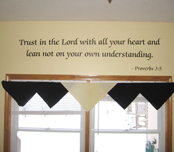 A bible verse wall quote below the window with black and white window drapery