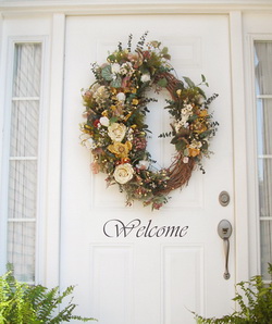 A white colored front door with a WELCOME word and an ornamental flower decor on the center.